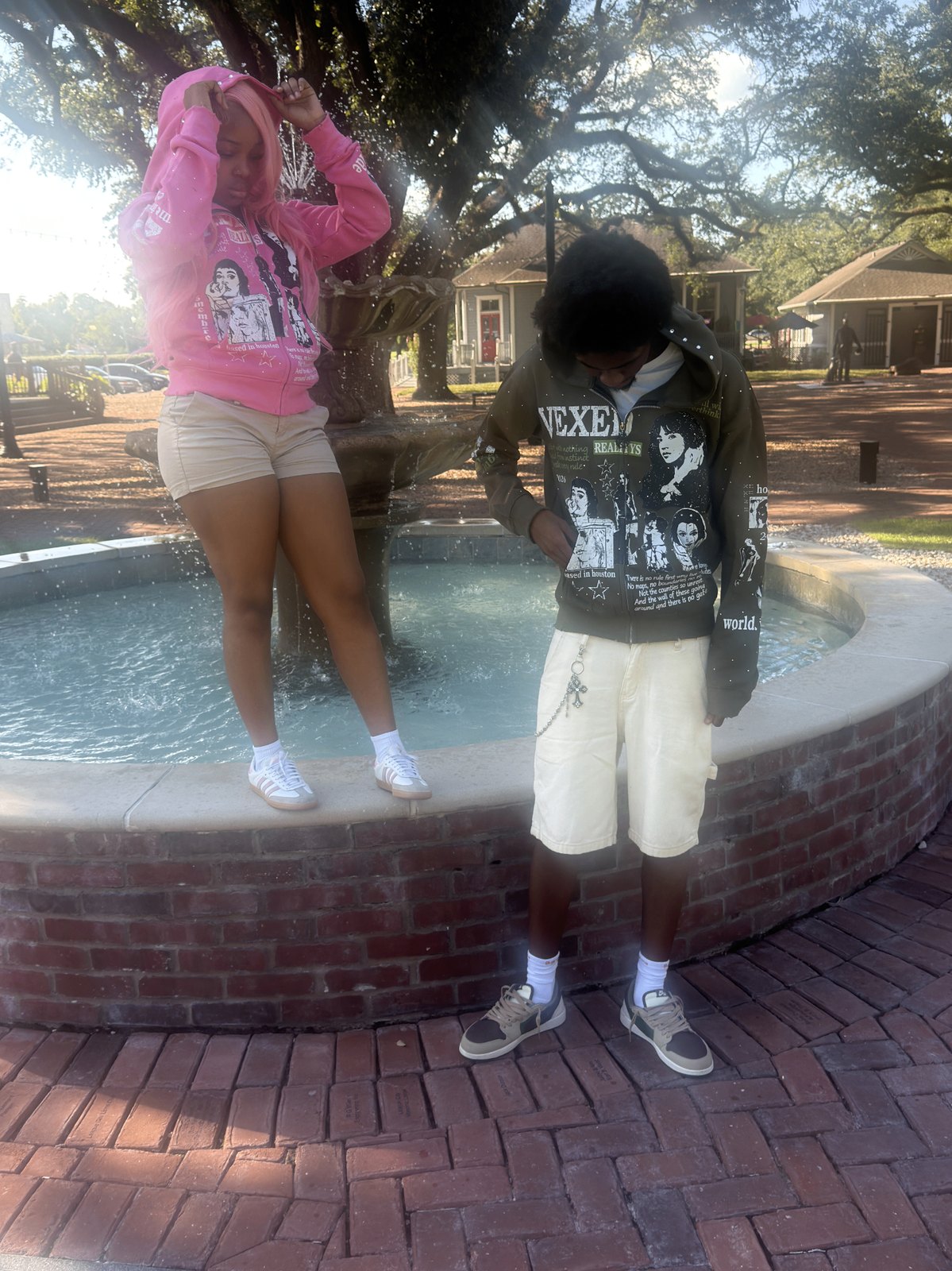 Vexed Realitys hoodies worn by two people beside a fountain